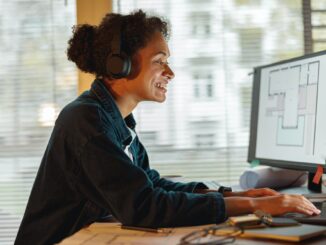 Smiling Afro american woman interior designer in headphones works in home office