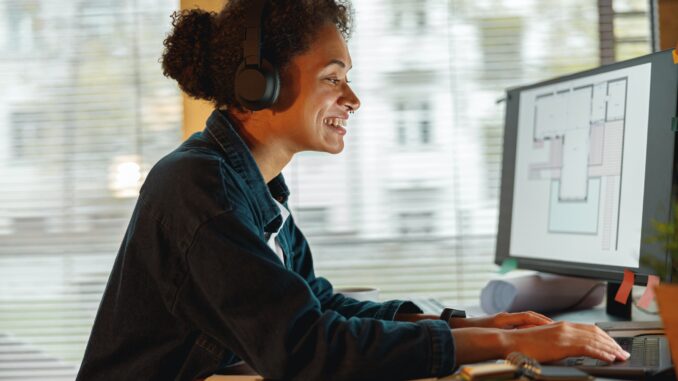 Smiling Afro american woman interior designer in headphones works in home office